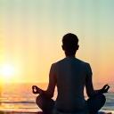 Uma pessoa meditando serenamente à beira-mar, simbolizando saúde mental e mindfulness.